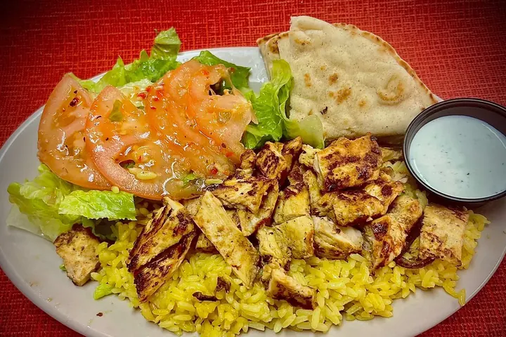 Our Chicken Kebob Plate: grilled chicken on yellow rice, with salad, pita and a cup of dressing