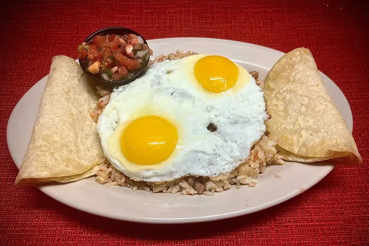 Our Huevos Ranchero: two sunny side up eggs on rice and beans, with tortillas and a cup of salsa
