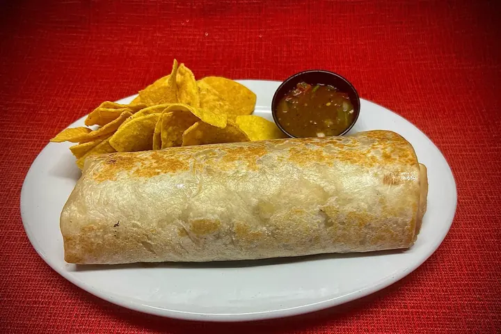 Our carne asada burrito on a white plate with a cup of salsa